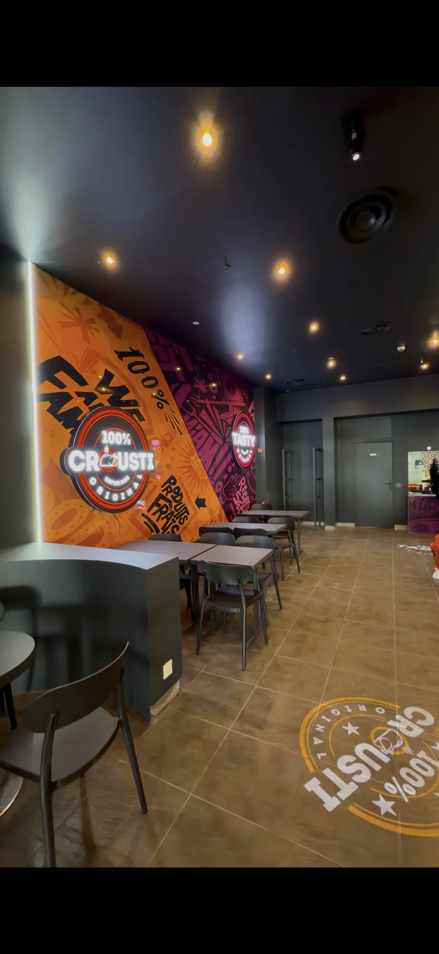 Intérieur d’un restaurant 100% Crousti avec fresque murale de la marque